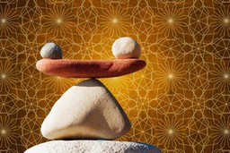 Setting Intentions. Some stones in careful balance. The stones are different shades, and one has an orange hue. The background is an amber sacred geometry pattern.
