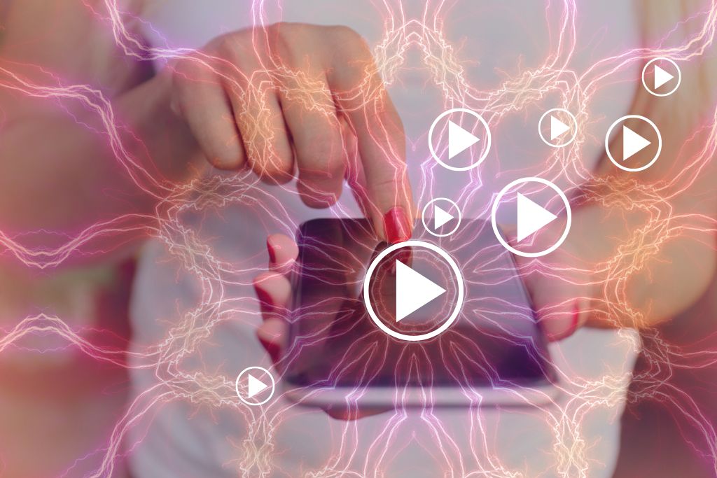 Music for a Therapeutic Psychedelic Trip. Image is of a mobile phone facing upwards, held by a light-skinned feminine hands, with one hand holding the phone, and the other touching the screen with an index finger. They are wearing red nail polish. There are psychedelic mandala-like patterns emanating from the phone, as well as music 'play' symbols of various sizes.