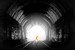 The power of darkness. The image depicts the interior of a dark tunnel with a bright white light at its end, creating a striking contrast. The tunnel walls are textured, showing rugged details in shades of black and gray. At the center, near the light source, is the silhouette of a glowing orange human figure in a dynamic pose, standing on railroad tracks that lead out of the tunnel. The composition directs the viewer&#039;s eye from the dark surroundings toward the light, emphasizing the figure as a focal point. The overall mood is dramatic and symbolic, blending darkness and illumination effectively.