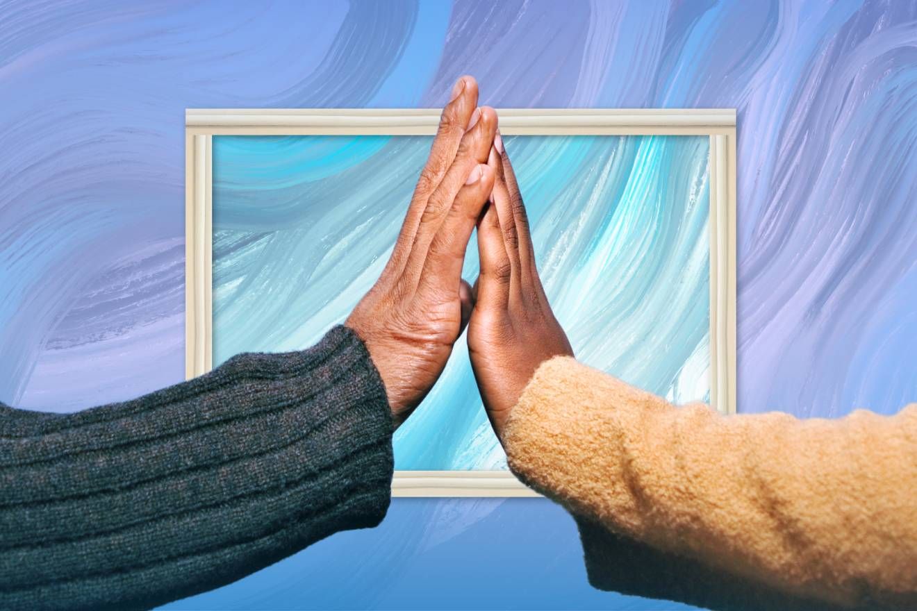 Therapeutic touch. A photograph of a hand from each of two people held up to each other. The person on the left is wearing a dark blue-grey jersey, and the one on the right is wearing a mustard yellow one. In the background is a marbled purple, blue and whte background with a white frame around part of it.