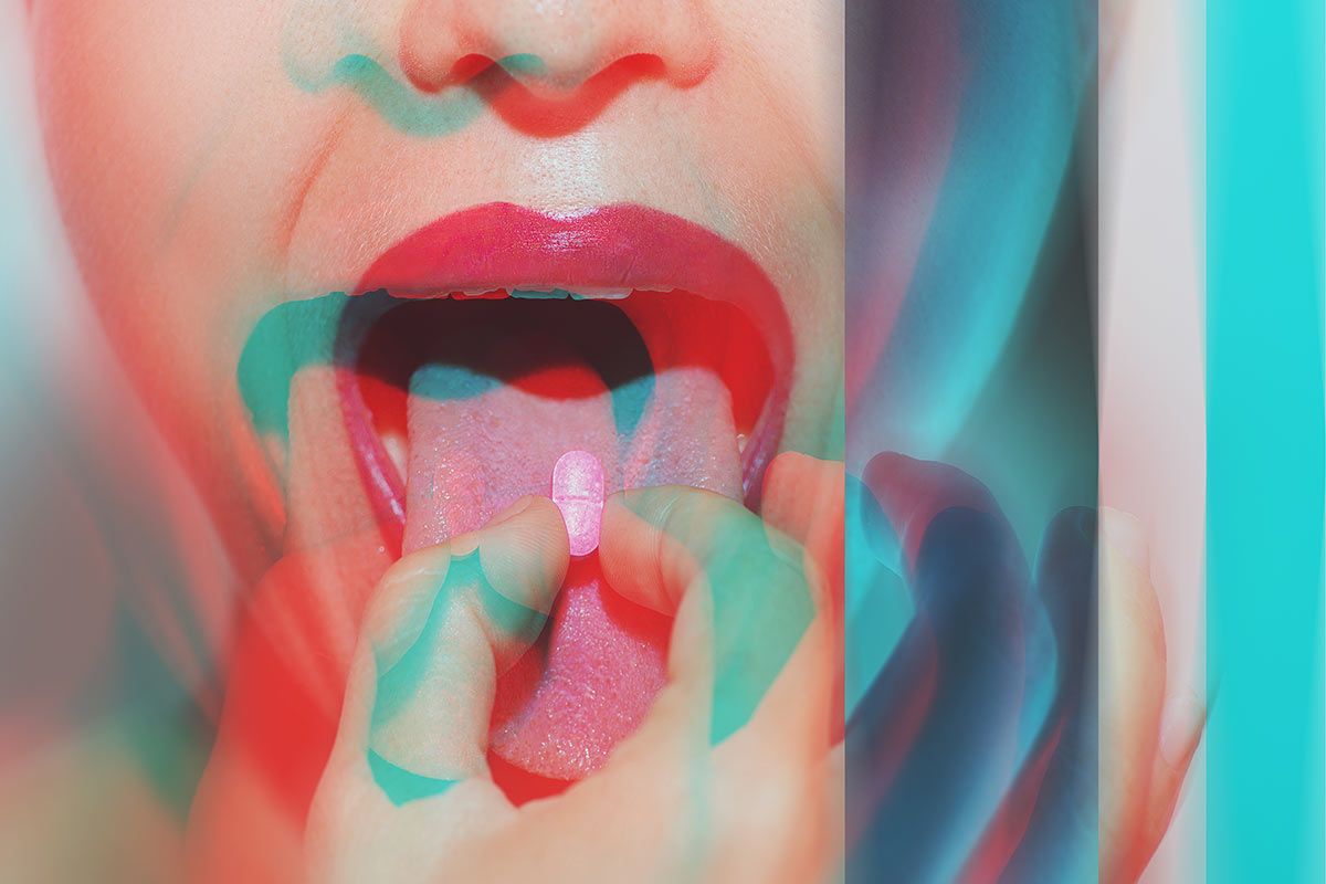 Young woman with MDMA tablet on tongue