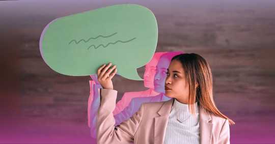 Psychedelics and Language. The image features a young woman with long brown hair, wearing a light beige blazer and a white top, holding a large green speech bubble with squiggly lines drawn on it. The background has a wood-like texture in soft brown tones, transitioning into a gradient of purple and pink hues at the bottom. The woman’s figure is artistically duplicated with pink-tinted semi-transparent overlays, creating a layered, reflective effect. The composition is dynamic, with a modern and creative visual aesthetic.