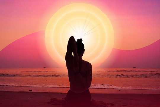 After the Ceremony. The image showcases a serene beach scene during what appears to be sunrise or sunset. At the center is the silhouette of a person sitting in a meditative yoga pose, with one arm stretched behind their back, creating a peaceful and balanced composition. The background features a gradient sky transitioning from soft pinks to warm oranges, blending seamlessly with the bright sun radiating concentric circular patterns of light. The calm ocean reflects the warm hues, while the figure is perfectly framed against the glowing sun, emphasizing a sense of harmony and spirituality.